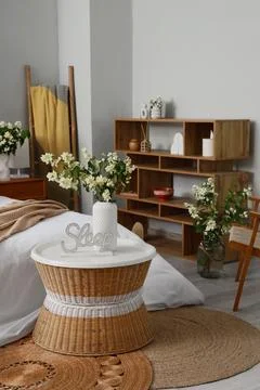 Cozy bedroom corner with wicker table and floral decor Stock Photos