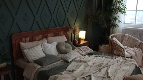 Cozy bedroom interior in boho style with green walls, wooden furniture, craft Stock Footage 234822942