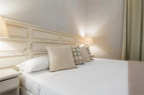 Cozy bedroom interior with rustic white headboard and warm lighting Fotos de archivo