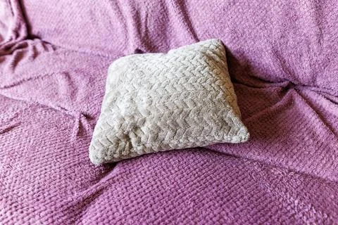 Cozy beige pillow rests on soft purple textured fabric Stock Photos