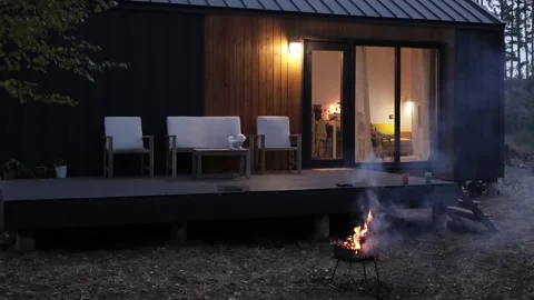 A Cozy Cabin at Dusk Featuring a Fire Pit for Relaxation and Family Gatherings Stock Footage 308895656