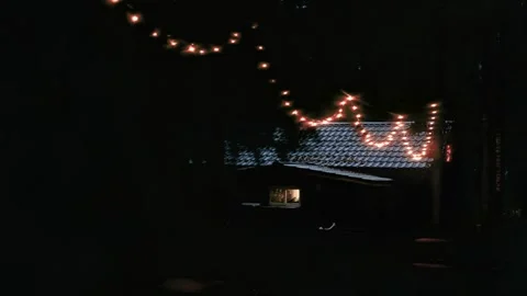 Cozy cabin illuminated by string lights at night with gradual camera zoom in Stock-Footage 322070634