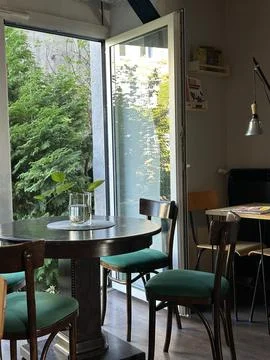 Cozy cafe interior with round table by window and green view Stock Photos