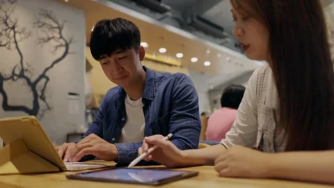 In a cozy cafe setting, two young entrepreneurs engage in a lively discussion Stock Footage 247038659