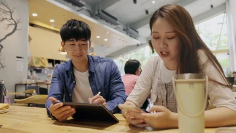 In a cozy cafe setting, two young entrepreneurs engage in a lively discussion Stock Footage 247038820