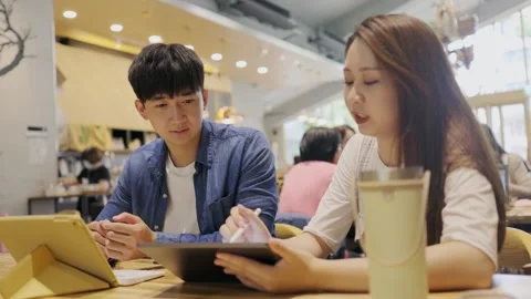 In a cozy cafe setting, two young entrepreneurs engage in a lively discussion Stock Footage 247038868