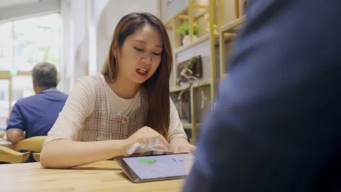 In a cozy cafe setting, two young entrepreneurs engage in a lively discussion Stock Footage 247039306