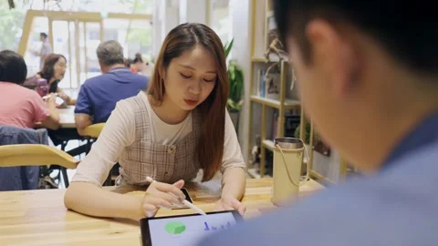 In a cozy cafe setting, two young entrepreneurs engage in a lively discussion Stock Footage 247039463