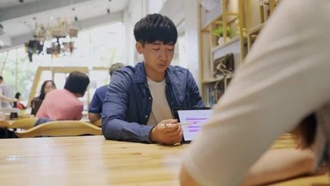 In a cozy cafe setting, two young entrepreneurs engage in a lively discussion Stock Footage 247039840