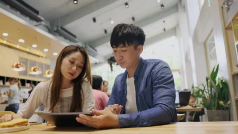 In a cozy cafe setting, two young entrepreneurs engage in a lively discussion Stock Footage 247039966