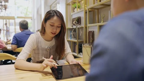 In a cozy cafe setting, two young entrepreneurs engage in a lively discussion Stock Footage 247041046