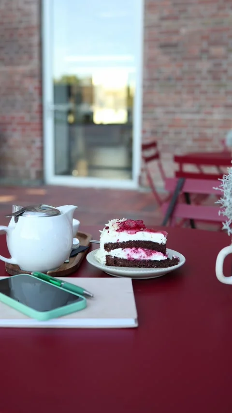 Cozy cafe table with berry cake teapot smartphone and notebook Stock Footage 344447257