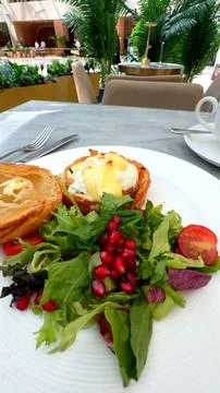 In cozy cafe white plate on table holds a delicious breakfast of croissant, egg Stock Photos