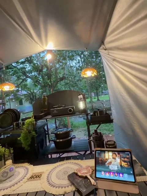 Cozy Camping Tent Setup with Hanging Lights and Kitchen Gear 库存影片 341317787