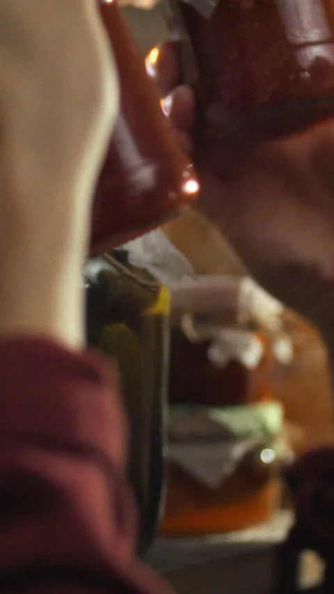 In a cozy cellar lit by warm light a man examines a jar of fermentation prod 스톡 동영상 334397618