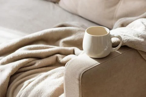 Cozy ceramic mug with soft blanket on sofa under warm natural light cozy ho.. Stock Photos