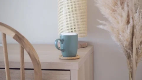 Cozy coffee mug on side table near lamp and tall dried grass decoration. Stock Footage 332116351