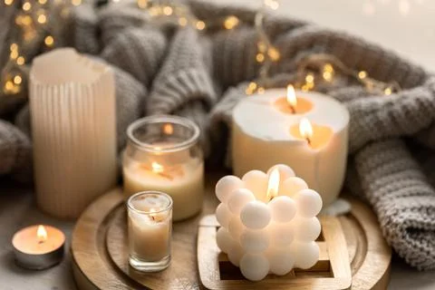 A cozy composition with candles, a knitted element and a garland. Stock Photos