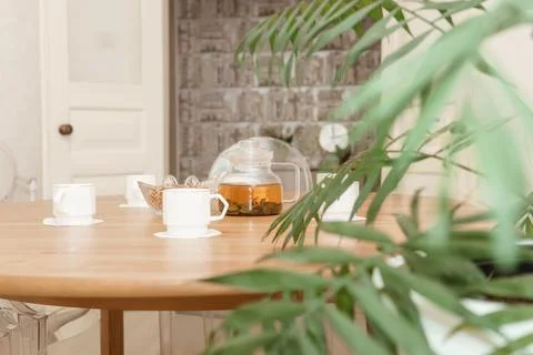 A cozy composition featuring a teapot and cups on a round wooden table, Stock Photos