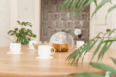 A cozy composition featuring a teapot and cups on a round wooden table, Stock Photos