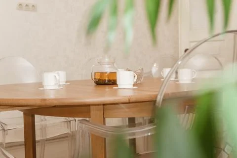 A cozy composition featuring a teapot and cups on a round wooden table, Foto stock