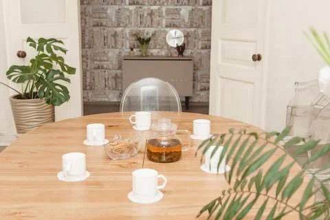 A cozy composition featuring a teapot and cups on a round wooden table, Stock Photos