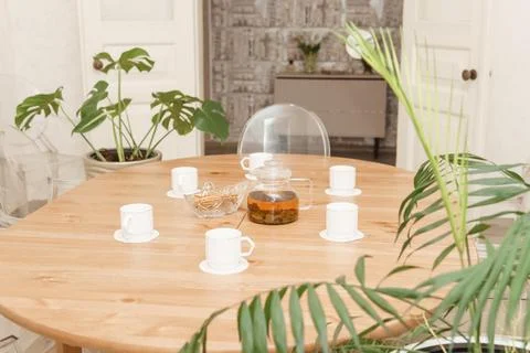 A cozy composition featuring a teapot and cups on a round wooden table, Stock Photos