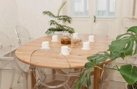 Cozy dining setting featuring a round wooden table surrounded by transparent Foto stock