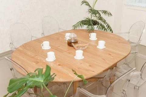 Cozy dining setting featuring a round wooden table surrounded by transparent Stock Photos