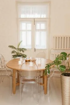 Cozy dining setting featuring a round wooden table surrounded by transparent Foto stock