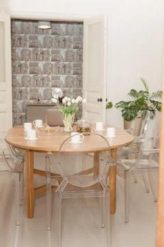 A cozy dining setup, featuring a wooden table with a laptop, tea set, and tul Stock-Fotos