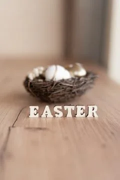 A cozy Easter nest filled with white and speckled eggs sits on a wooden sur.. Stock Photos