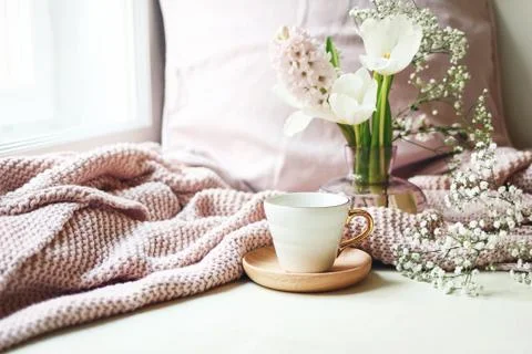 Cozy Easter, spring still life scene. Cup of coffee, pink knitted plaid and Fotos Stock