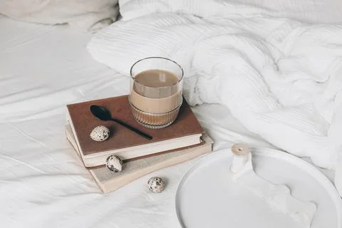 Cozy Easter, spring still life scene. Cup of coffee in glass, books and quail Foto stock