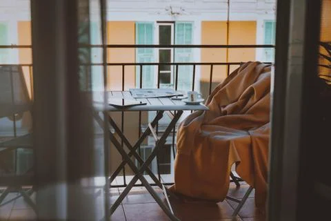 Cozy empty terrace, balcony with table, chair, blanket, newspaper, coffee Stock Photos