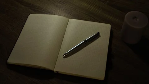 Cozy evening planning routine with a white candle, open notebook and glasses Video stock 338192005