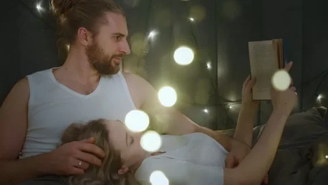 Cozy evening reading together in a softly lit bedroom Stock Footage 300347145