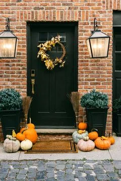 Cozy fall entrance with pumpkins and autumn decor in brick setting Stock Photos