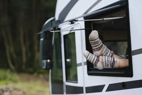 Cozy feet in patterned wool socks sticking out of camper window during a re.. 写真素材