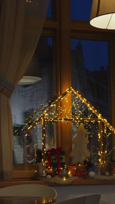 Cozy festive interior, Cozy window display featuring tiny lit house and seasonal Video stock 325126474