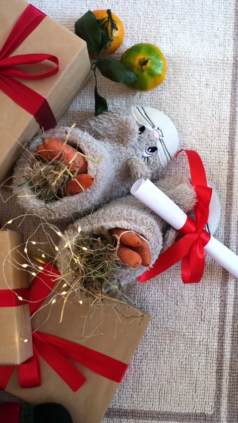 Cozy festive scene featuring plush bunny slippers filled with carrots and a Stock Footage 318717982