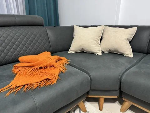 Cozy gray sofa with orange throw blanket at home Stock Photos