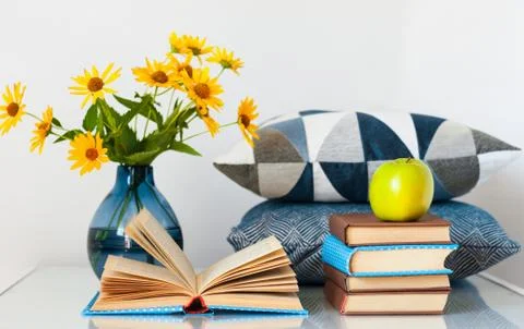 Cozy home interior decor: stack of books, green apple, decorative pillows and Stock Photos