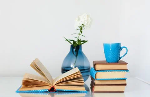 Cozy home interior decor: stack of books, cup of coffee and vase with white f Stock Photos