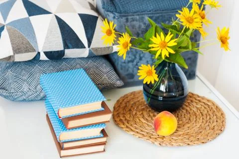 Cozy home interior decor: stack of books, peach, decorative pillows, box with Stock Photos