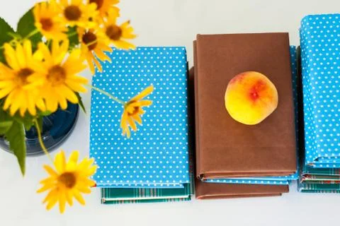 Cozy home interior decor: stack of books, peach and vase with yellow flowers  Stock Photos