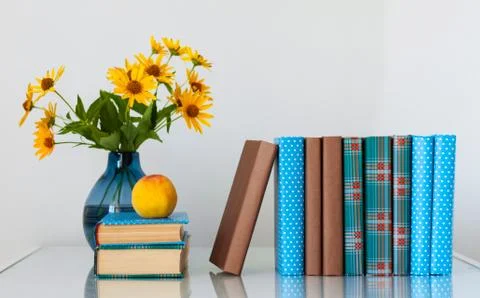 Cozy home interior decor: stack of books, peach and vase with yellow flowers  Stock Photos
