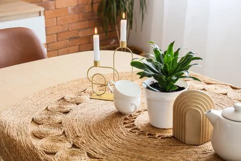 Cozy home interior with dining table, woven jute runner, lit candles, potted  Stock Photos