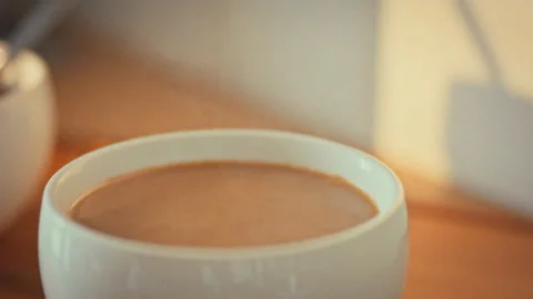 In cozy home kitchen a cup of steaming Turkish coffee with milk sits slowly Stock Footage 333831162