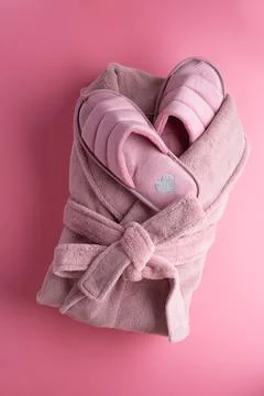 Cozy home set with slippers and bathrobe against pink background. concept com Stock Photos